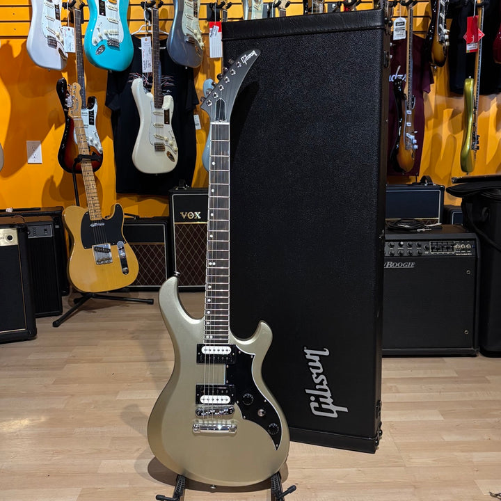 Gibson Victory, Gold Mist Satin. Reintroduced 80s-era cult-favorite solidbody electric. Mahogany body with refined contours. Explorer headstock. 25.5-inch scale SlimTaper mahogany neck, compound radius ebony fretboard, 24 medium jumbo frets. 80s Tribute humbuckers with push/pull master volume and tone controls for coil splitting. Tune-O-Matic bridge, Stop Bar tailpiece. Satin nitrocellulose lacquer finish. Includes hardshell case.